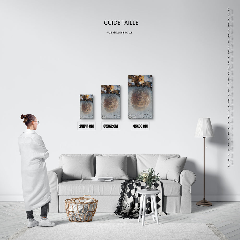 Guide des tailles : le tirage présenté dans ses 3 formats de vente, à l'échelle réelle sur un mur de salon, avec une règle en centimètres.