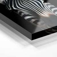 Gros plan de la matière : le tirage sous verre acrylique, tranche transparente visible.