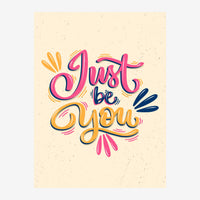 Affiche avec lettrage coloré « Just be you » en rose, jaune et bleu sur fond beige clair avec motifs décoratifs.