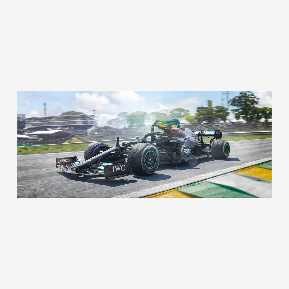Une monoplace de course noire et turquoise lancée à grande vitesse sur un circuit automobile, avec des stands et des arbres.