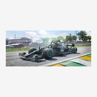 Une monoplace de course noire et turquoise lancée à grande vitesse sur un circuit automobile, avec des stands et des arbres.
