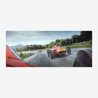 Vue dynamique d'une monoplace orange et jaune en course sur un circuit de montagne sinueux, prise depuis un véhicule.