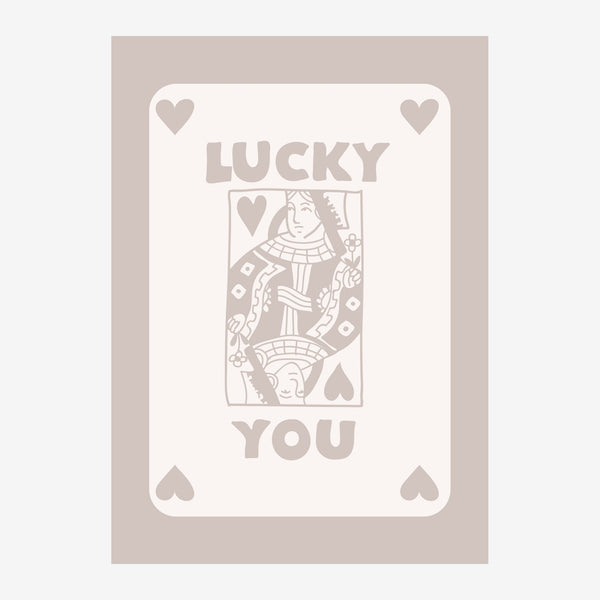 Affiche portrait avec une reine de cœur stylisée au centre, encadrée de cœurs et du texte "LUCKY YOU" sur fond beige et gris.