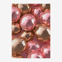 Composition de boules à facettes rose et cuivre brillantes, arrangées densément sur un fond pourpre.