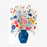 Un vase bleu rempli d'un bouquet dense de fleurs multicolores : roses roses, bleuets bleus, coquelicots rouges, marguerites.