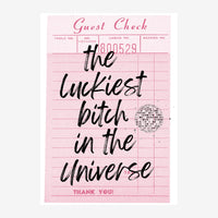 Affiche rose poudré imitant un reçu de restaurant avec texte manuscrit « the luckiest bitch in the universe » et un miroir.