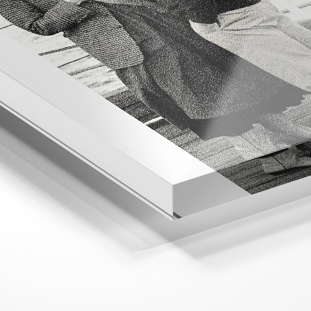 Gros plan de la matière : le tirage sous verre acrylique, tranche transparente visible.