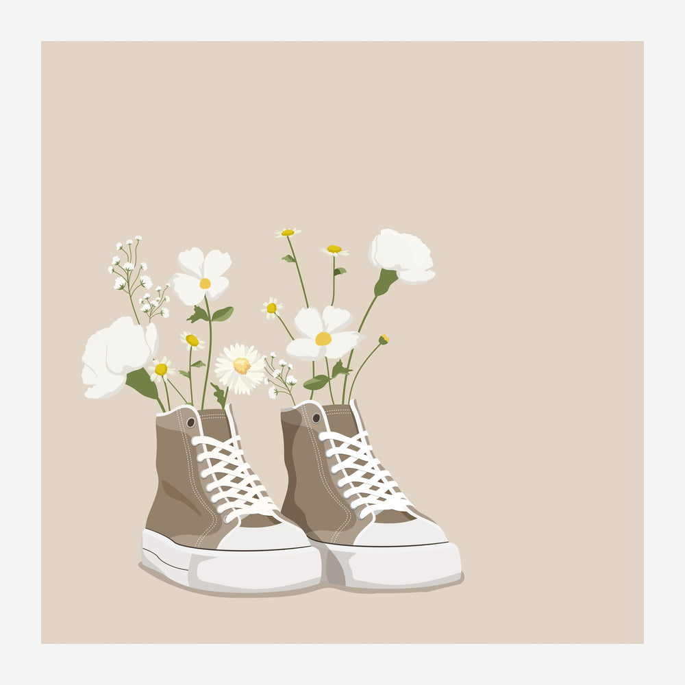 Deux baskets en toile beige et blanc avec lacets blancs, remplies d'un bouquet de marguerites blanches et jaunes avec tiges.