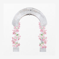 Une arche architecturale en pierre blanche avec deux colonnes ornées de fleurs roses grimpantes de chaque côté, sur fond.