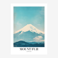 Affiche de voyage représentant le Mont Fuji enneigé avec ses pentes blanches dominant des montagnes bleues sous un ciel.