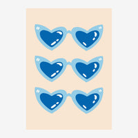 Trois paires de lunettes en forme de cœur, remplies de bleu foncé avec des reflets blancs, sur un fond beige clair.